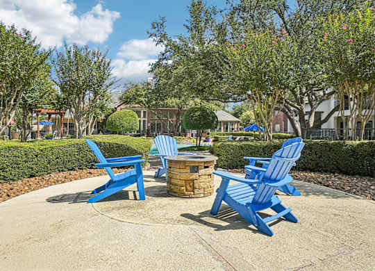 A park with blue chairs and a fire pit.