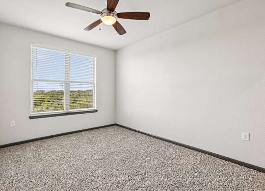 A room with a ceiling fan and a window with blinds.
