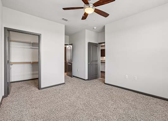 A room with a ceiling fan and a white wall.