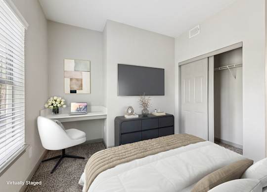 A bedroom with a bed, desk, and chair.