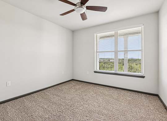 A room with a ceiling fan and a window with blinds.