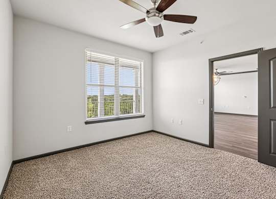 A room with a ceiling fan and a window with blinds.