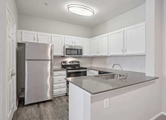 A kitchen with white cabinets and a stainless steel refrigerator.