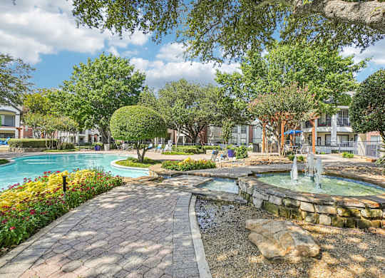 A beautiful outdoor scene with a fountain, trees, and a swimming pool.
