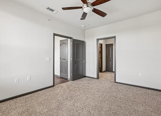 A room with a ceiling fan and two doors.