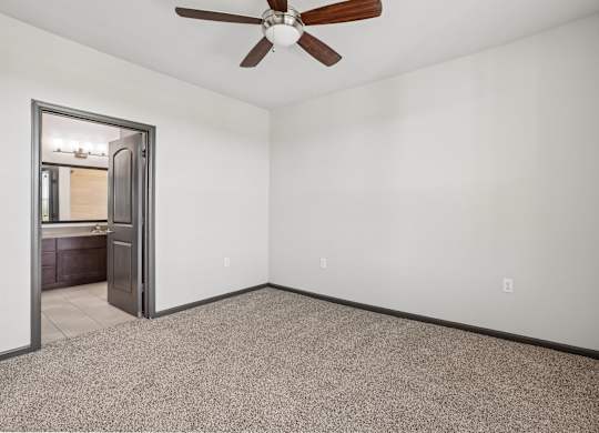 A room with a ceiling fan and a door leading to another room.