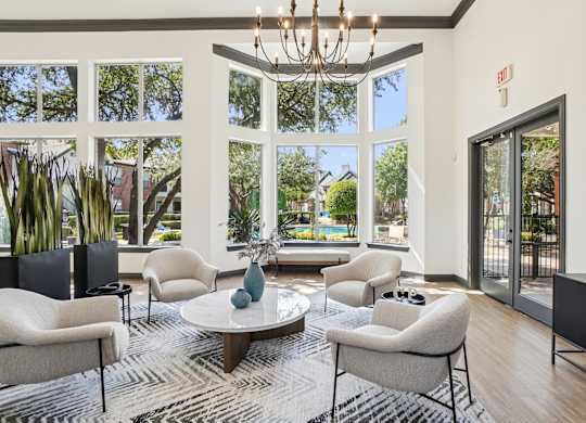 A living room with a chandelier, a sofa, a chair, a table, and a rug.
