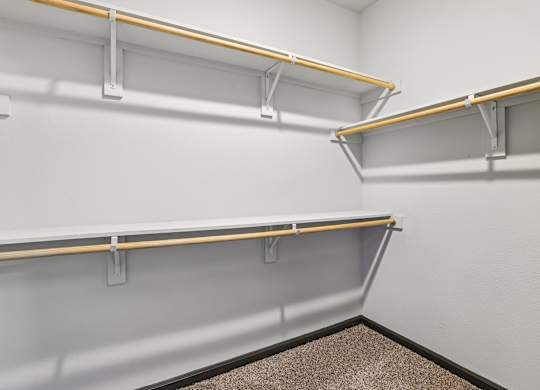 A white wall with a grey carpet and three shelves with yellow bars.