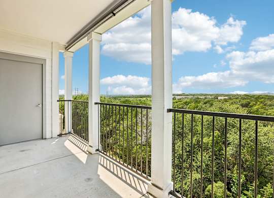 A balcony with a view of a green landscape.