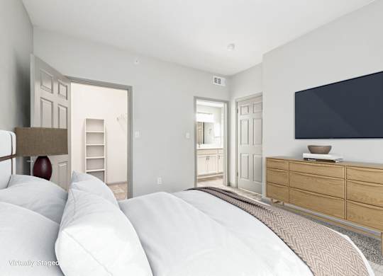A bedroom with a large bed and a flat screen TV mounted on the wall.