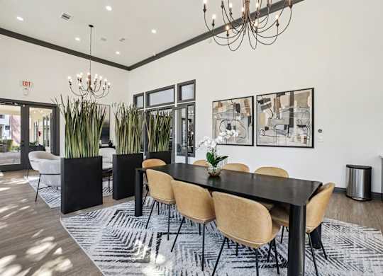 A black dining table with six chairs and a chandelier hangs above it.