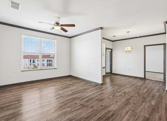 A room with a ceiling fan and a window overlooking a building.