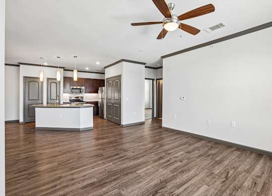 A modern kitchen with a wooden floor and a ceiling fan.