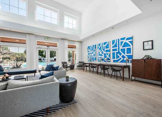 A modern living room with a grey sofa and a large abstract painting on the wall.