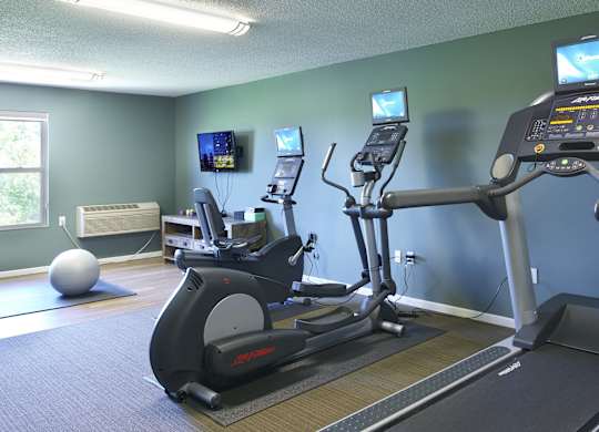 a gym with exercise equipment and televisions on the wall