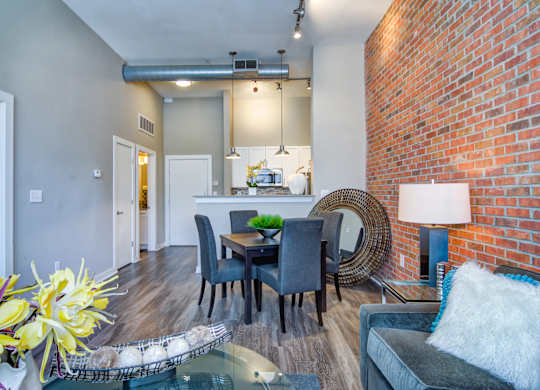 Pet-Friendly Apartments in Atlanta, GA - Biltmore at Midtown - Luxury Living and Dining Area with Exposed Brick Wall