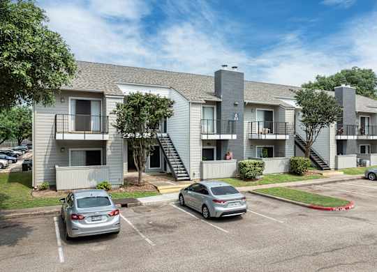 an apartment building with cars parked in a parking lot