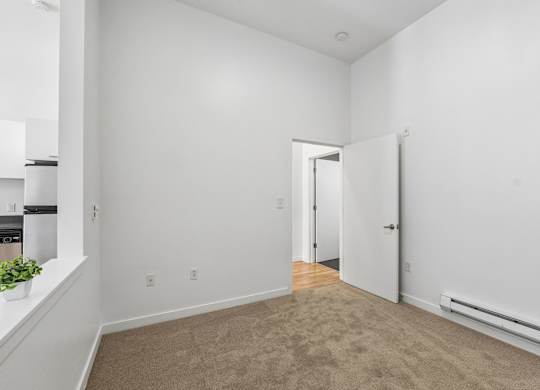 A room with a carpeted floor and a doorway leading to another room.