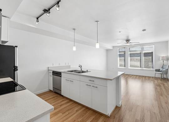 A modern kitchen with white cabinets and a wooden floor.