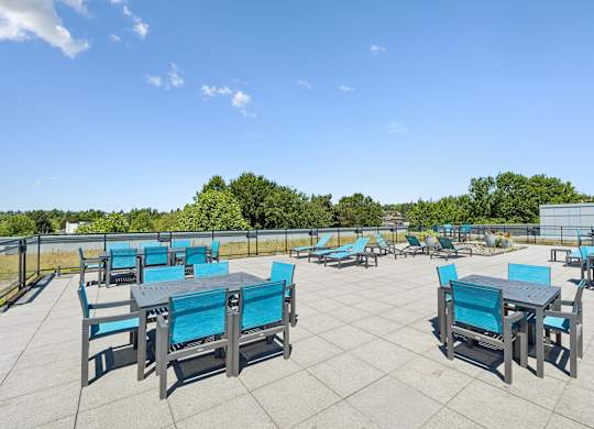 A patio with blue chairs and tables is set up for outdoor dining.