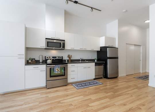 A modern kitchen with wooden floors and stainless steel appliances.
