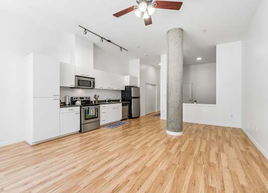 A kitchen with white cabinets and a wooden floor.