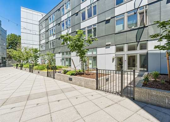 A modern building with a glass facade and a metal fence in front.