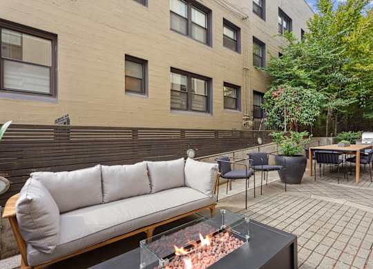 a patio with a couch and tables and a fire pit