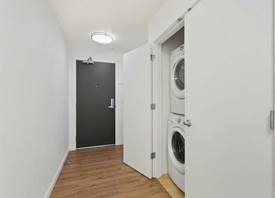a washer and dryer in a white room with a black door
