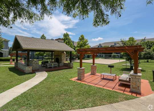 A gazebo is surrounded by a brick patio and a stone wall.