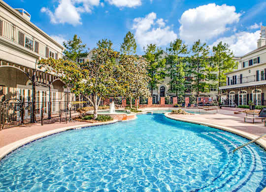 Washington Avenue Coalition, TX, Luxury Apartments Near Upper Kirby - Marcella Memorial Heights - A Swimming Pool Surrounded By Elegant Buildings, Lush Landscaping, And Sun Loungers.