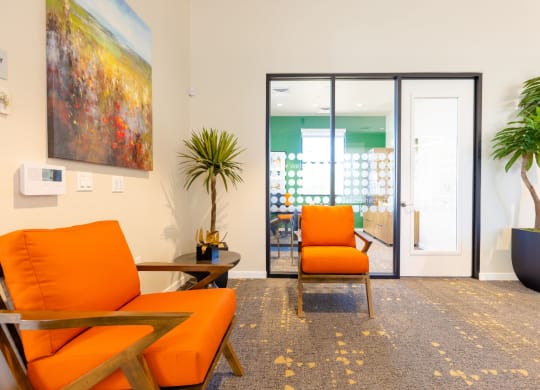 a living room with orange chairs and a sliding glass door
