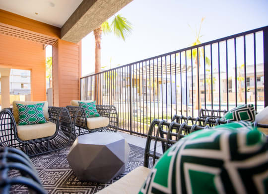 a living room with chairs and a table and a balcony with palm trees