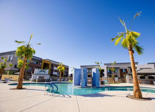 a swimming pool with palm trees and buildings in the background