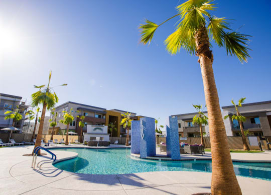 a swimming pool with palm trees and buildings in the background