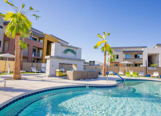 a swimming pool with palm trees and apartments in the background