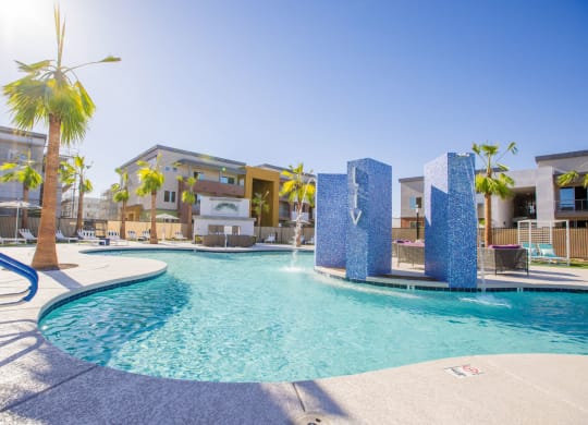 a swimming pool with palm trees and apartments in the background