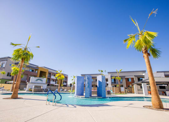a swimming pool with palm trees and apartments in the background