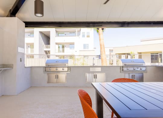 a patio with a table and chairs and two barbecue grills