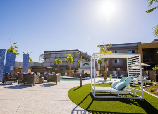 a patio with lounge chairs and a pool at a hotel with palm trees