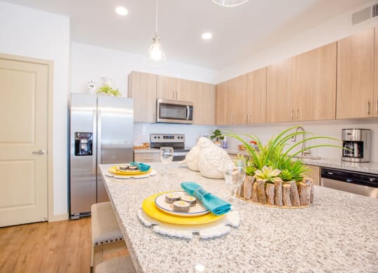 Pet-Friendly Apartments In Gilbert, AZ - Kitchen With Granite Countertops, Stainless Steel Appliances, Dishwasher, Tile Backsplashes, And Plank Flooring.