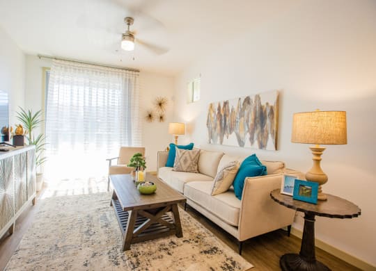 Apartments in Gilbert, AZ for Rent - Curve At Gilbert - Living Room With A Ceiling Fan, Plank Flooring, And A Sliding Glass Door To A Private Patio/Balcony