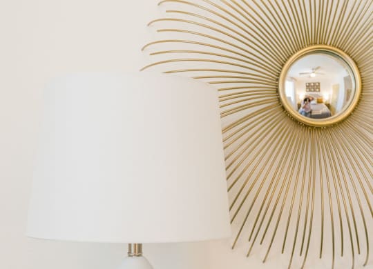 a white table with a lamp and a mirror on the wall