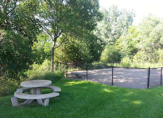 a picnic table in a park next to a fence
