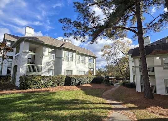A white apartment building with a tree in front.