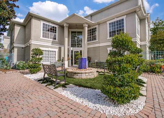 Luxury One-Bedroom Apartments in Houston, TX - The Maroneal - Exterior View of the Leasing Office with Benches, a Fountain, and Beautiful Landscaping
