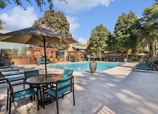 A patio with a table and chairs and a pool in the background.