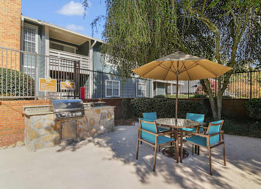 A patio with a table, chairs and an umbrella.
