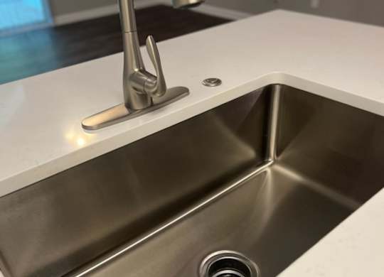a stainless steel sink with a tap in a kitchen