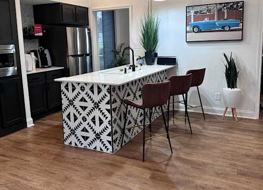 a kitchen with a large white island with a black and white geometric pattern